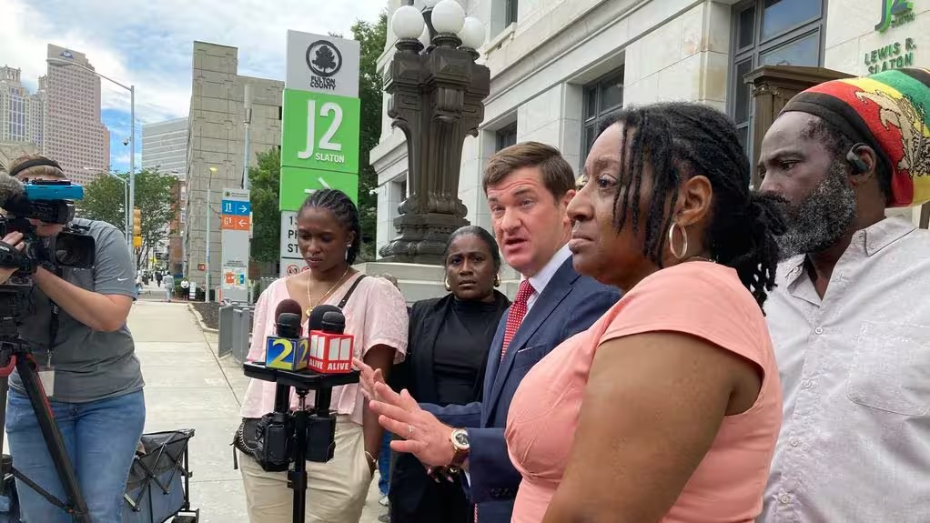 Attorney Parker Miller (center) and Mari Creighton's parents, Tracey Eason and Juan Umberto Creighton (far right), outside the Fulton County courthouse. Photo Courtesy The Atlanta Constitution.